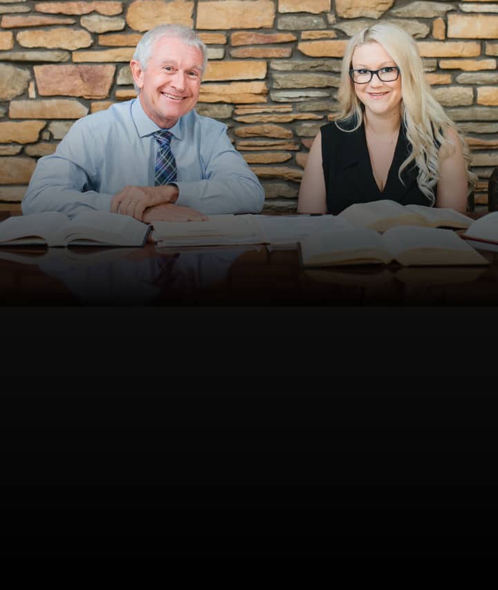 Two law professionals smiling at a desk